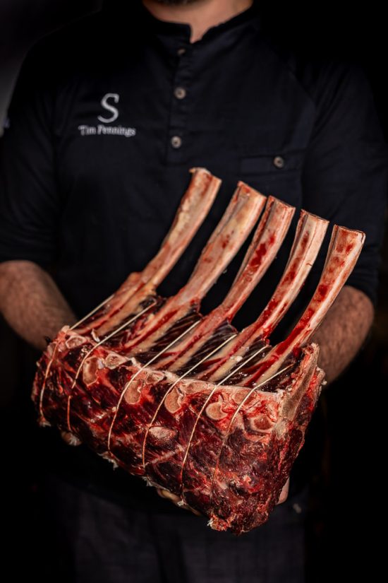 chef stoked holds tomahawk steaks in hand